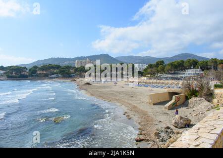 Peguera, Mallorca, Espagne - 05.01.2022: Personnes sur la plage hors saison à Peguera, Majorque. Maisons sur des collines en arrière-plan. Banque D'Images