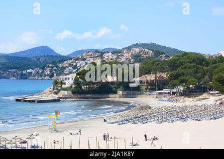 Peguera, Mallorca, Espagne - 05.01.2022: Personnes sur la plage hors saison à Peguera, Majorque. Maisons sur des collines en arrière-plan. Banque D'Images