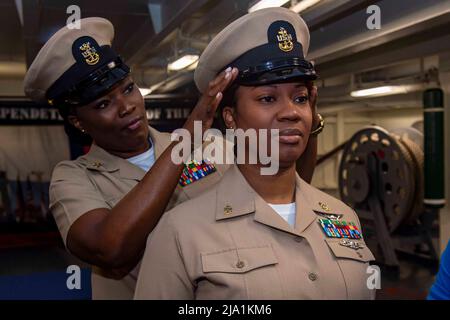 Yokosuka, Japon. 17th mai 2022. LaSandra Garcia, administratrice principale en chef de la maintenance de l'aviation, reçoit sa nouvelle couverture combinée de la part de la spécialiste en chef de la logistique principale Georgette Spaulding lors d'une cérémonie d'épinglage du maître-chef et du premier chef de la petite militaire dans la piste du seul porte-avions déployé par l'avant de la marine américaine, l'USS Ronald Reagan (CVN 76). Au cours de la cérémonie, quatre nouveaux maîtres-chefs et 20 nouveaux officiers supérieurs ont été épinglés par des amis et des membres de la famille. Ronald Reagan, le navire amiral du Carrier Strike Group 5, fournit une force prête pour le combat Banque D'Images