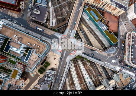 Une vue aérienne directement au-dessus d'une métropole urbaine avec croisement de rue au-dessus de lignes de chemin de fer très fréquentées Banque D'Images