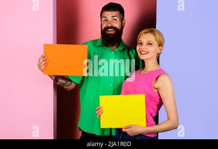 Couple souriant présentant un tableau publicitaire. Bannières vides avec espace de copie pour le texte. Shopping. Vente. Banque D'Images