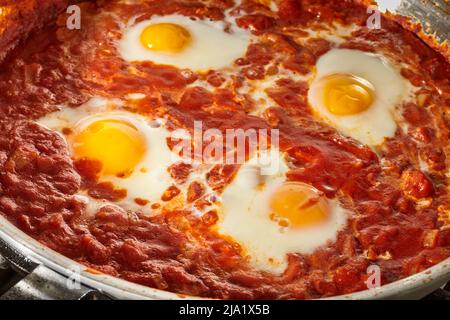 Shakshuka, le plat israélien de sauce aux œufs et aux tomates, cuisant dans une poêle en acier. Banque D'Images