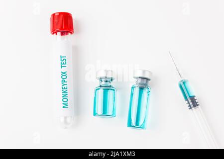 Tube de prélèvement sanguin pour le test du virus de la variole du singe et seringue avec vaccin forment la varicelle sur fond blanc. Concept médical. Vue de dessus. Banque D'Images