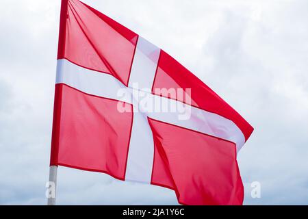 Drapeau du Danemark sur fond blanc ciel nuageux. Drapeau danois agitant dans le vent. Banque D'Images