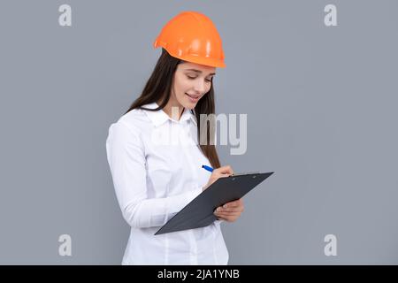 Femme d'affaires avec presse-papiers, portrait sur gris. Portrait d'une femme employée dans un casque de casque. Banque D'Images