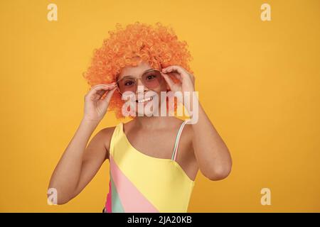 drôle d'enfant dans la perruque de clown. s'amuser. enfant porter des lunettes de soleil et un maillot de bain. Banque D'Images