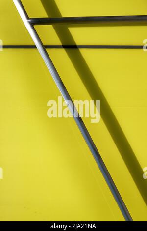 image d'arrière-plan détaillée de barres métalliques contre un mur vert jaune par temps ensoleillé Banque D'Images