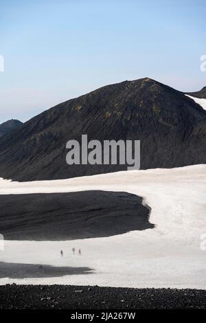 Randonneurs au loin sur un champ de neige, paysage volcanique vallonné de Barren de neige et de sable de lave, sentier de randonnée de Fimmvoerouhal, Porsmoerk nature Banque D'Images