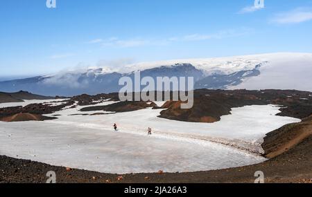 Deux randonneurs sur un sentier de randonnée à travers un champ de neige, paysage volcanique vallonné aride de de champs de neige et de lave, glacier Myrdalsjoekull dans le Banque D'Images