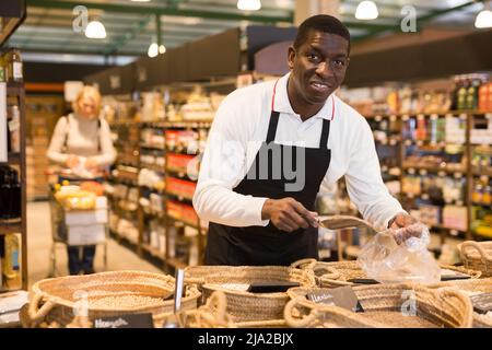 Homme travaillant dans le département de l'alimentation en vrac du supermarché Banque D'Images