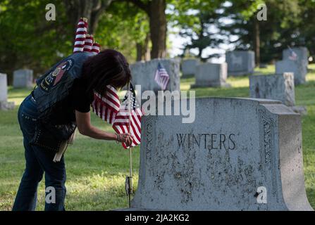 Dallas, États-Unis. 25th mai 2022. Une femme remplace un drapeau sur une tombe pour le jour du souvenir. Des membres de la Légion américaine, des scouts et des éclaireuses ont remplacé des drapeaux lambés dans les cimetières en vue de la fête du souvenir. Crédit : SOPA Images Limited/Alamy Live News Banque D'Images