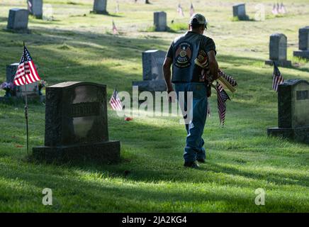 Dallas, États-Unis. 25th mai 2022. Un ancien combattant traverse un cimetière tout en portant des drapeaux pour remplacer les anciens drapeaux du jour du souvenir. Des membres de la Légion américaine, des scouts et des éclaireuses ont remplacé des drapeaux lambés dans les cimetières en vue de la fête du souvenir. Crédit : SOPA Images Limited/Alamy Live News Banque D'Images