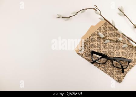 Branche de Salix caprea avec sacs-cadeaux en papier marron à motifs et verres noirs. Banque D'Images