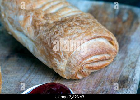 pâte feuilletée avec confiture de fraise rouge sur une table en bois, un petit pain fait de pâte de blé feuilletée et de garniture de fraise de baie Banque D'Images