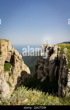 Paysage avec montagnes, collines et falaises. Un homme se tient sur une falaise et l'apprécie. Photo verticale. Banque D'Images