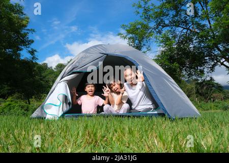 Bonne famille, mère et ses filles jouant ensemble dans une tente de camping au camping pendant des vacances d'été à la campagne. Banque D'Images