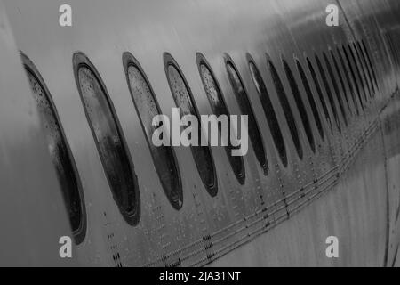 Vue sur le fuselage de l'avion et de nombreuses fenêtres baignées de pluie. Banque D'Images