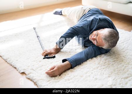 Man tombé sur tapis avec bâton de marche Banque D'Images