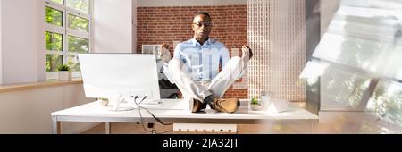 Young Businessman Sitting on Desk In Office Banque D'Images