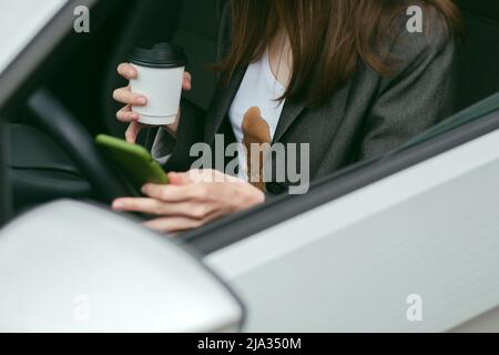 Une femme a renversé du café chaud sur elle-même en envoyant un SMS au téléphone en conduisant. Tâches quotidiennes sales Banque D'Images