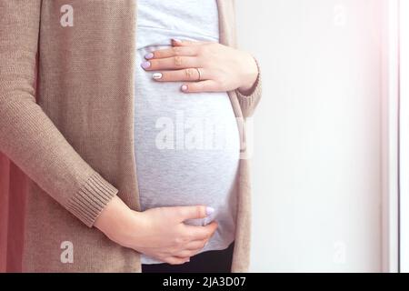 Femme enceinte près de la fenêtre. Gros plan. Banque D'Images