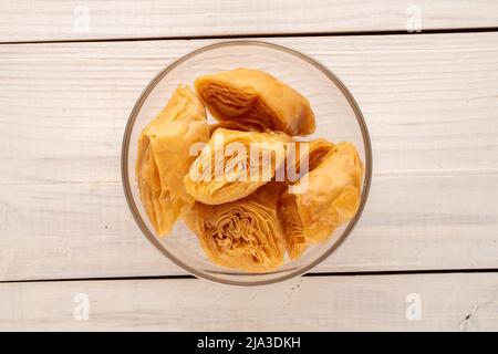 Plusieurs morceaux de baklava au miel sucré dans un bol en verre sur une table en bois, vue rapprochée, vue de dessus. Banque D'Images