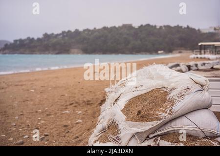 de grands sacs de sable en toile de jute ou en toile de jute arrêtant l'érosion du sol sur une plage pendant les jours de marée haute et de tempête Banque D'Images