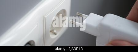 Insertion manuelle de l'alimentation de l'ordinateur portable dans la prise Banque D'Images