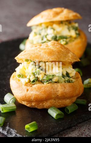 Apéritif pour les fêtes Profiteroles avec salade d'oeufs gros plan sur un tableau d'ardoise sur la table. Vertical Banque D'Images