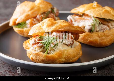 Apéritif épicé de profiteroles farcis aux champignons avec fromage à la crème et herbes dans une assiette sur la table Banque D'Images