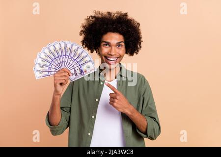 Portrait de la personne positive stupéfaite indique le doigt cent billets isolés sur fond beige couleur Banque D'Images