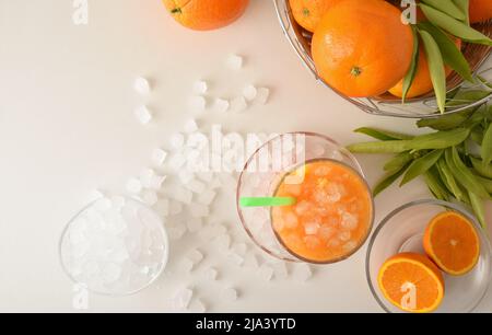 Détail de la boisson d'orange avec beaucoup de glace sur une table blanche avec des fruits et un bol avec de la glace autour d'elle. Vue de dessus. Composition horizontale. Banque D'Images