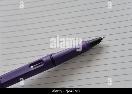 Le stylo plume violet se trouve sur une feuille de papier vide. Peur de l'ardoise propre. Copier l'espace Banque D'Images