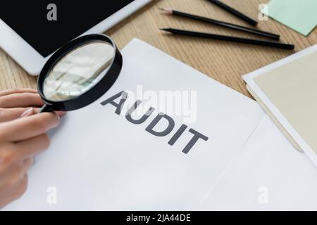 vue rognée de la femme tenant la loupe près du document d'audit Banque D'Images