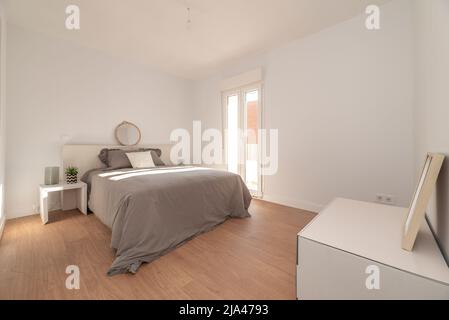 chambre récemment rénovée avec lit double et couvre-lit gris et accès à une terrasse d'angle Banque D'Images