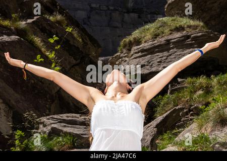 femme levant les bras sur la montagne dans une robe blanche Banque D'Images