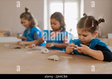 Groupe de petits enfants travaillant avec de l'argile poterie pendant la création artistique et cours d'artisanat à l'école. Banque D'Images