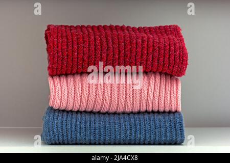 Pile de tissus de laine rouge, rose et bleue sur la tablette de la garde-robe blanche Banque D'Images