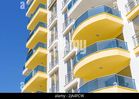 Façade moderne et aérée jaune et bleue avec fenêtres. Fragment d'un nouveau bâtiment résidentiel ou d'un complexe commercial. Partie de l'immobilier de ville. Banque D'Images