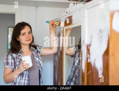 Femme fait des réparations dans l'appartement et peint placard Banque D'Images