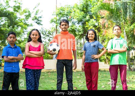 équipe d'enfants avec un football debout en toute confiance en regardant la caméra au parc - concept des champions, des aspirations et des activités de loisirs Banque D'Images