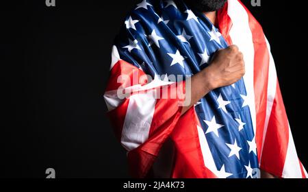 Le jeune homme priant en nous portant le drapeau en mettant la main sur le coeur - concept de contemplation et de liberté. Banque D'Images