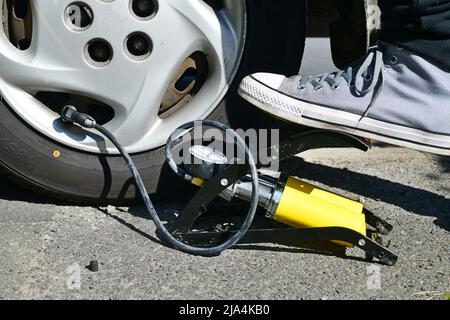 personne vérifiant la pression des pneus du véhicule et gonflant le pneu à l'aide du pied pompe Banque D'Images