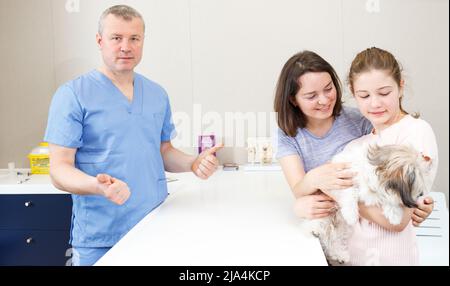 Famille heureuse avec le conseil de chien par vétérinaire Banque D'Images