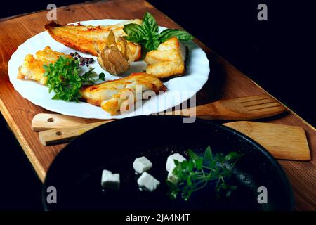 Filets de morue sur une assiette blanche avec fenouil et herbes sur une structure en bois, Banque D'Images