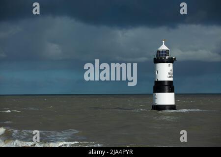 Trwyn du Lighthouse, également connu sous le nom de Penmon Lighthouse, sur une mer calme avec un ciel chargé de tempête de moody Banque D'Images