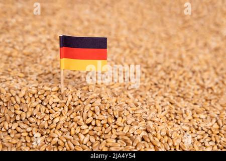 Drapeau allemand dans la pile de grain de blé comme arrière-plan. Concept de pénurie alimentaire, de crise de l'approvisionnement en céréales et de pénurie alimentaire mondiale en Europe et en Allemagne Banque D'Images