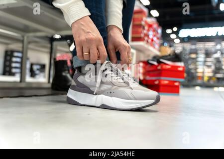 une fille essaie de nouvelles baskets dans un magasin de vêtements de sport Banque D'Images