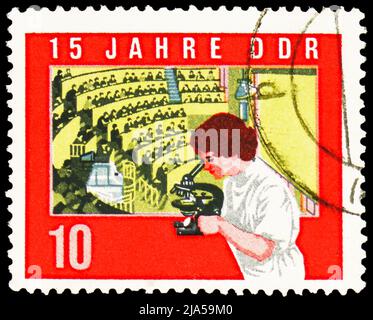 MOSCOU, RUSSIE - 14 MAI 2022: Timbre-poste imprimé en Allemagne montre étudiant avec microscope, salle de conférence, 15th anniversaire de la démocratique allemande Banque D'Images
