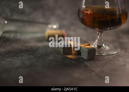 whisky transparent avec une bouteille et un liège en bois sur fond sombre. pierres de whisky dans un verre Banque D'Images